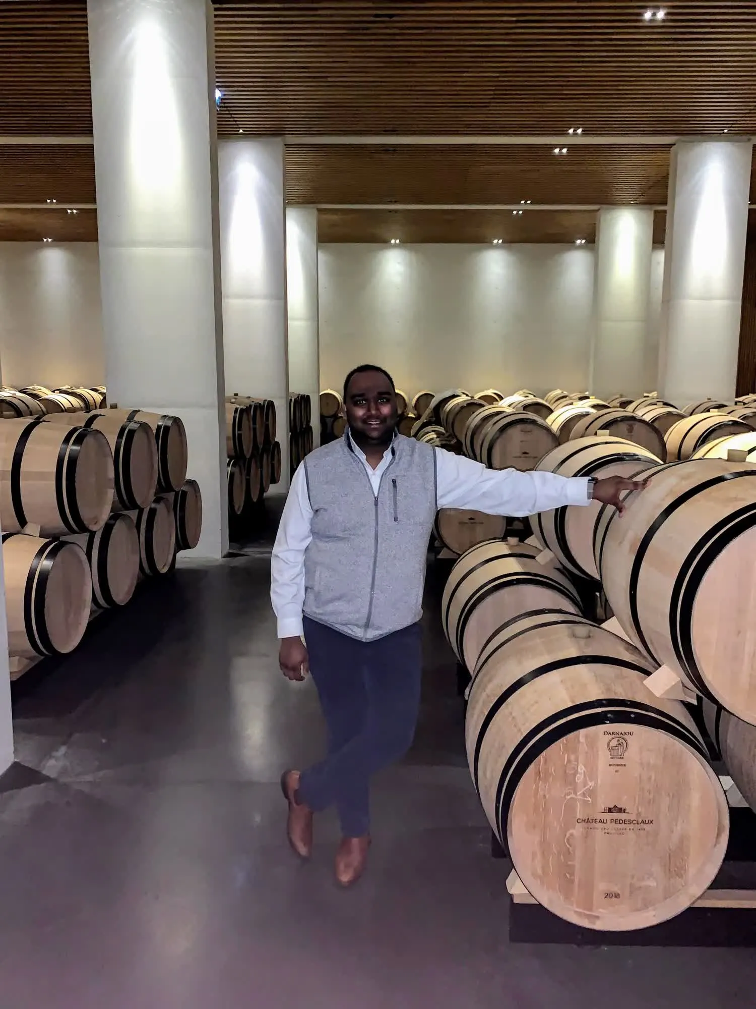 Yagna Vudathu, founder of Stave & Slate, among oak barrels in a Pauillac barrel hall